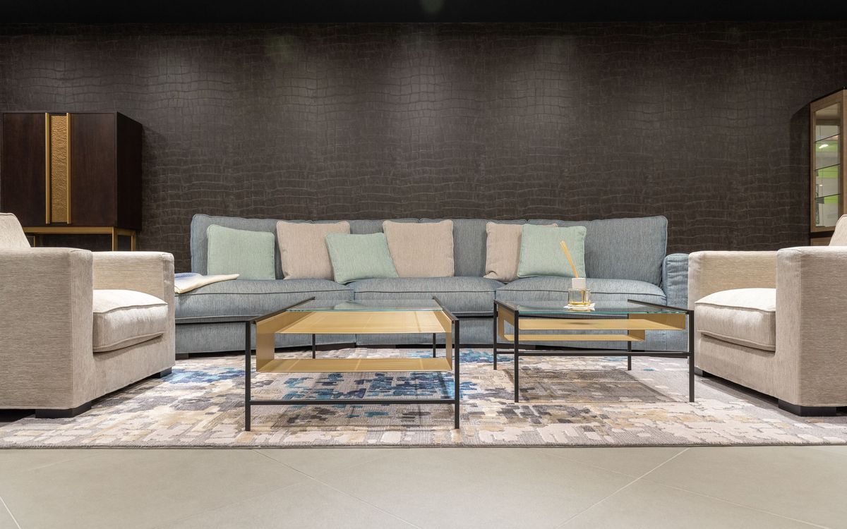 Comfortable gray sofa with colorful cushions and armchairs near tables on a carpet in a modern living room.
