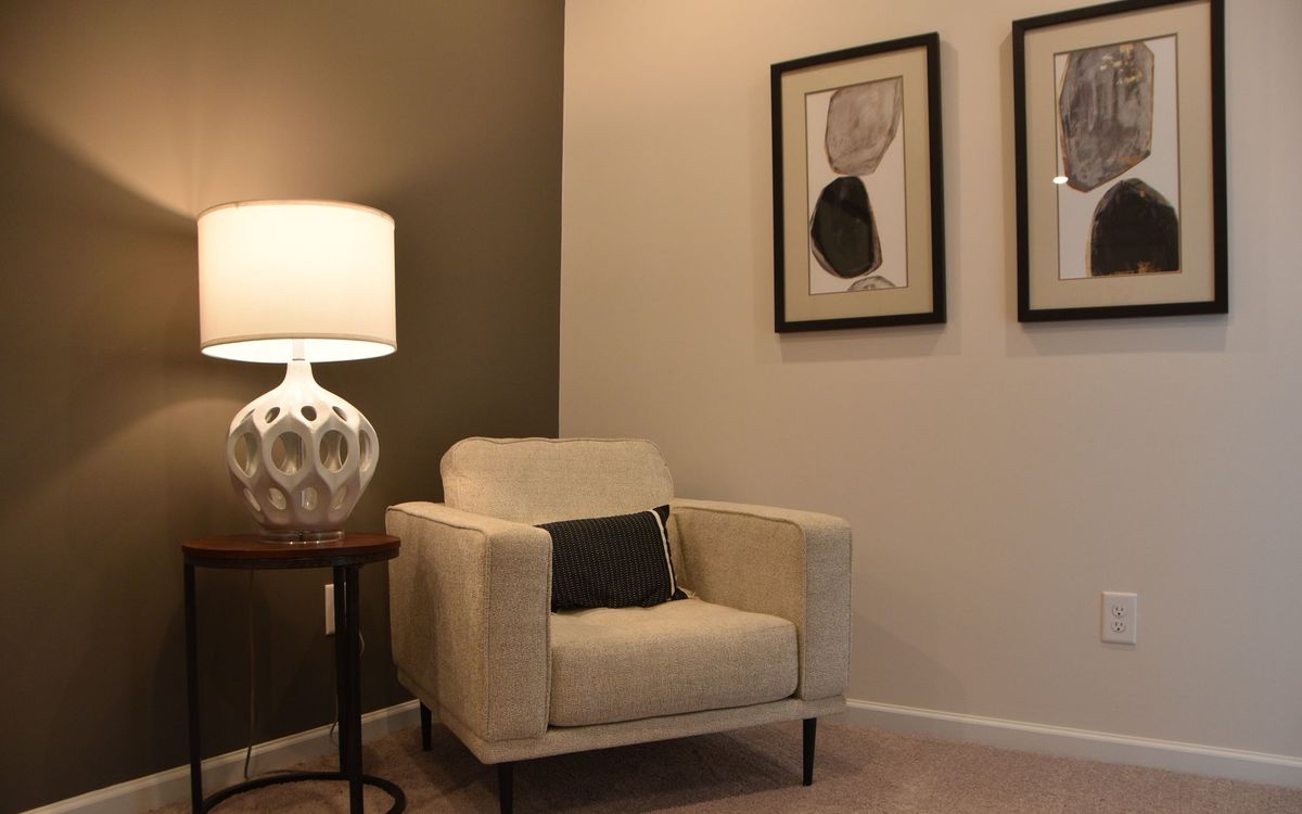 Elegant living room with a modern armchair, lamp and abstract art on the walls.