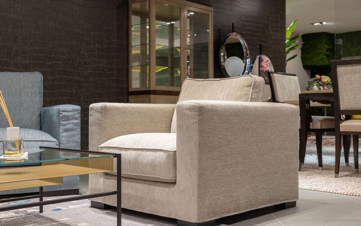 Interior of cozy light living room with comfortable armchairs near table with glass tabletop near cabinet