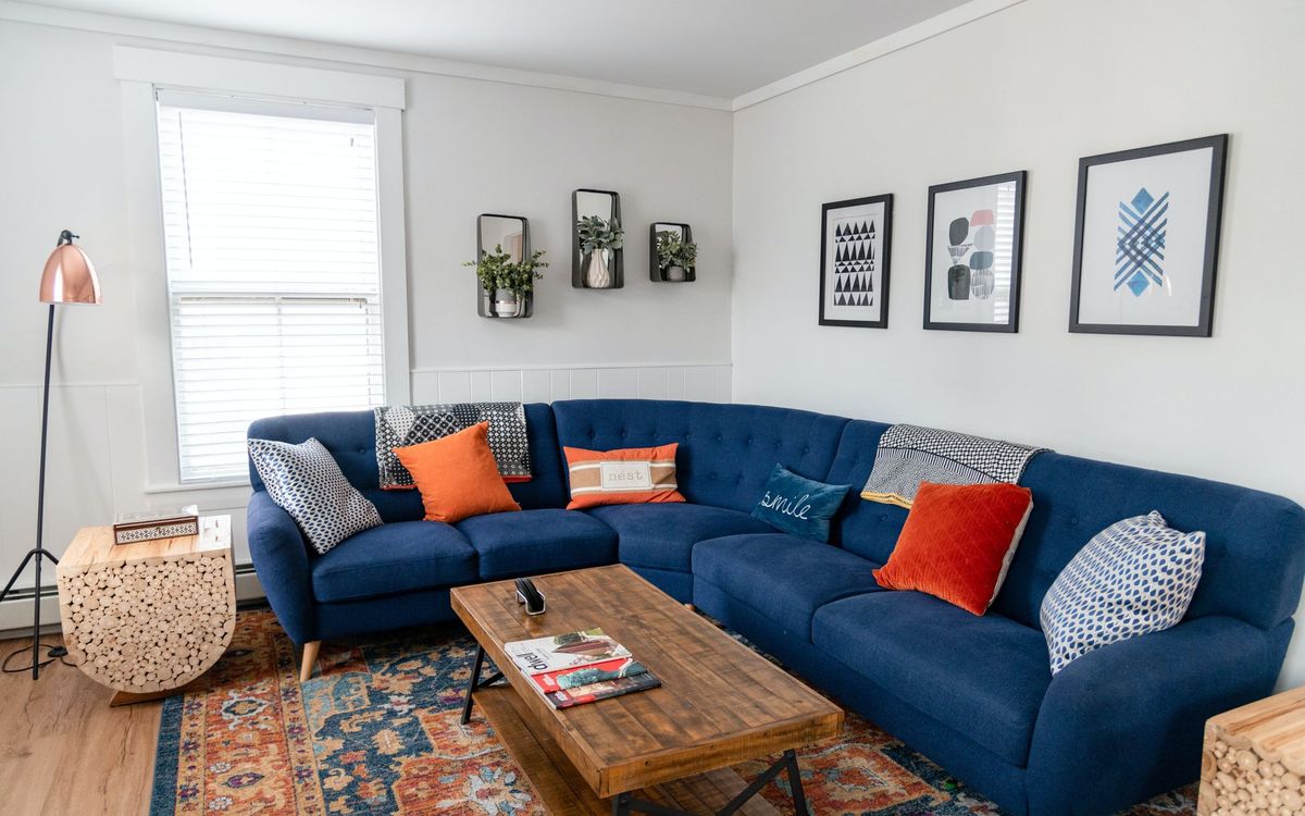Bright and stylish living room featuring a blue sectional, vibrant pillows, and modern decor.