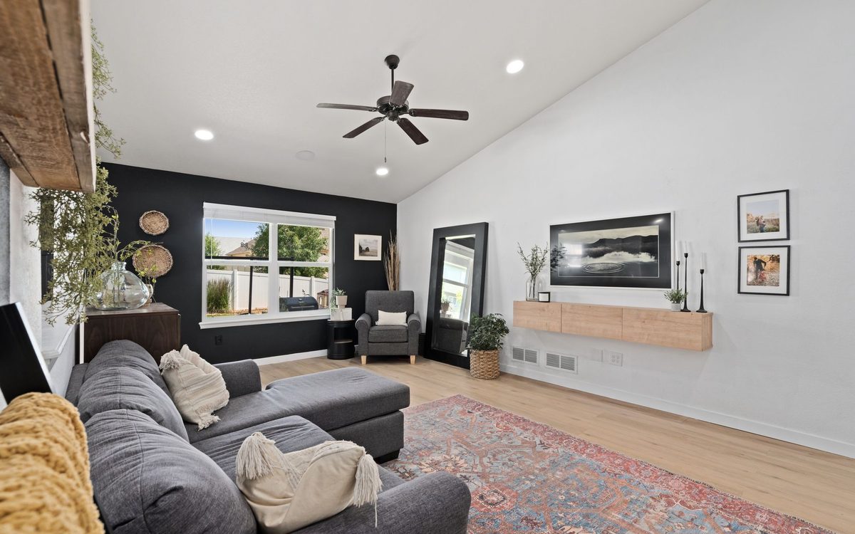 A stylish and cozy modern living room featuring a sectional couch, decorative elements, and natural light through large windows.