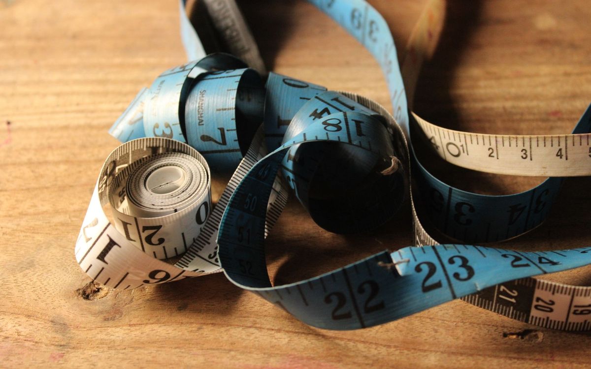 Measuring tape on a wooden floor to check space for a wingback recliner at home.