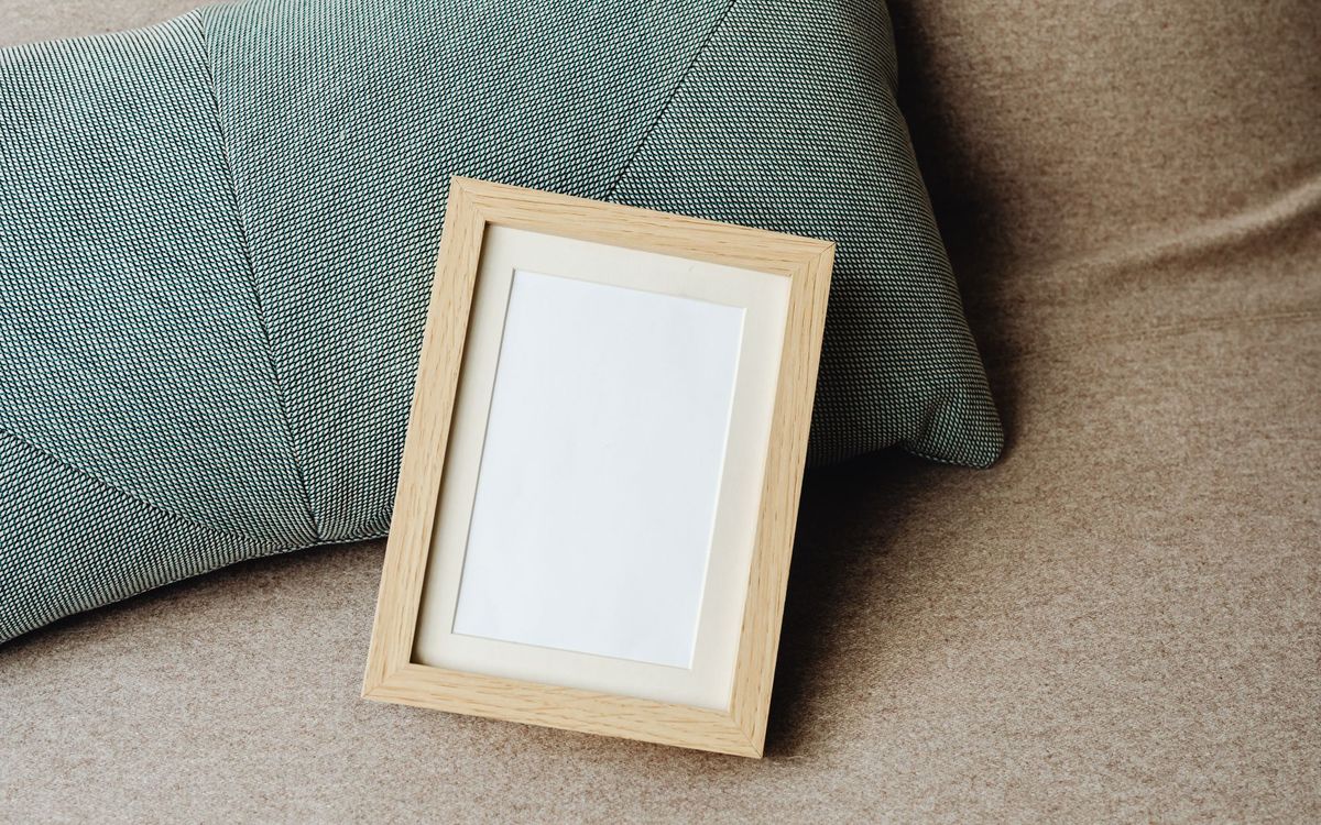 Minimalist image of a wooden frame and textured pillow on a sofa, ideal for mockups.