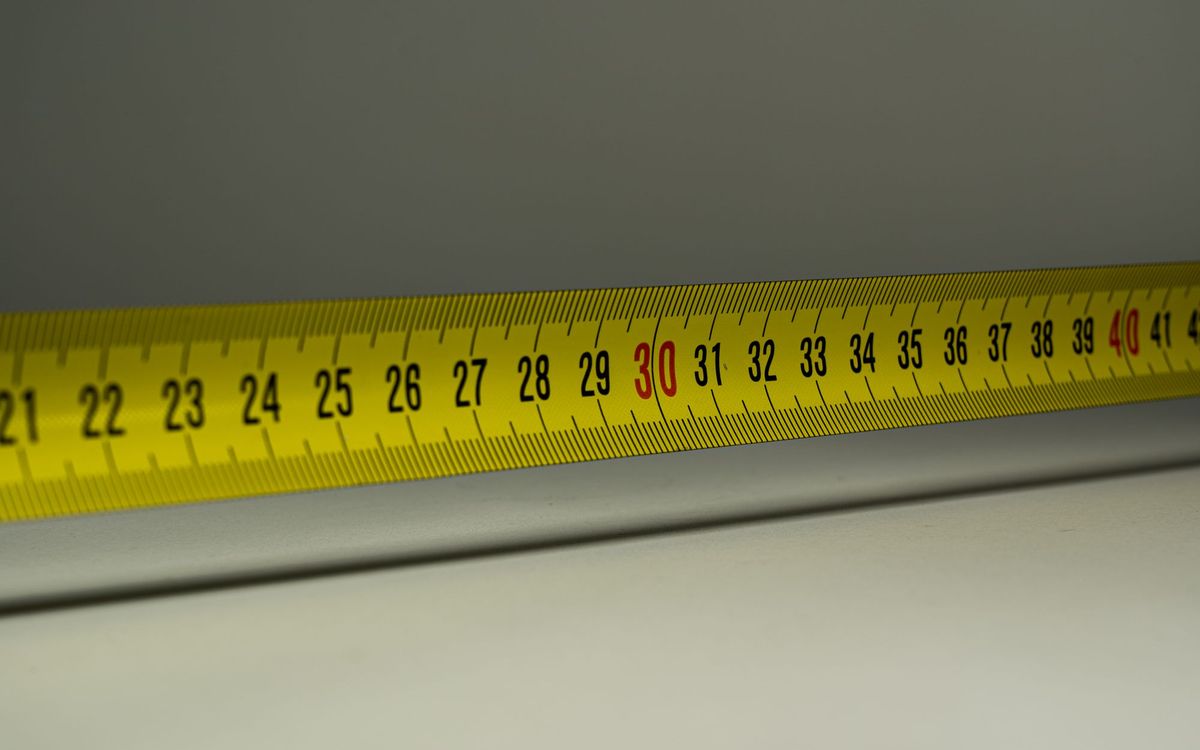 Close-up of a yellow tape measure lying along a gray surface