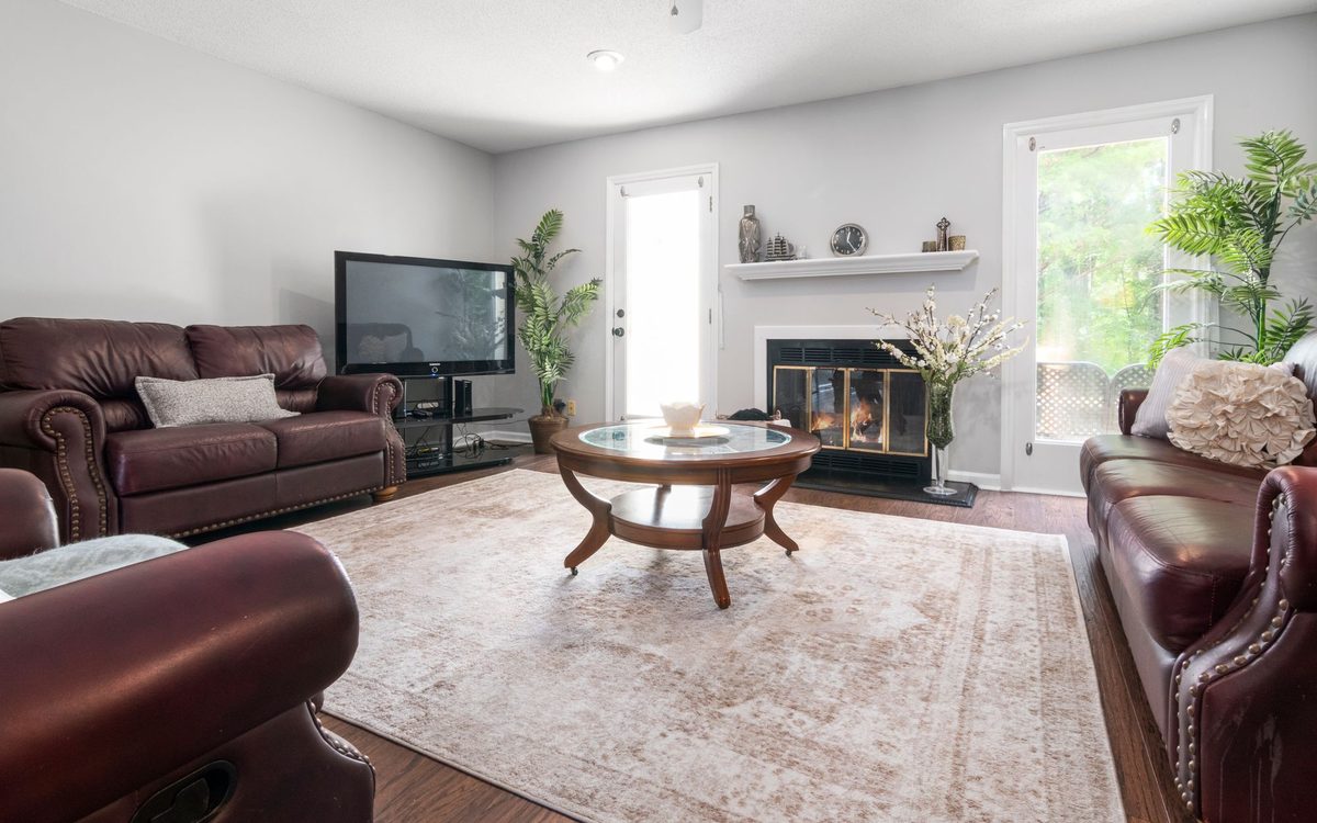 Living room with leather sofas and a leather recliner in the foreground, a round coffee table and a fireplace on the far wall