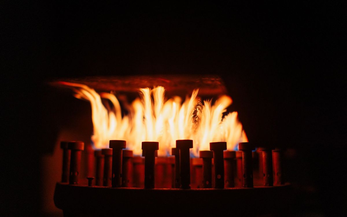 Gas burner jets with orange flames rising in a dark enclosure, the kind of burner parts that lava rocks should never block