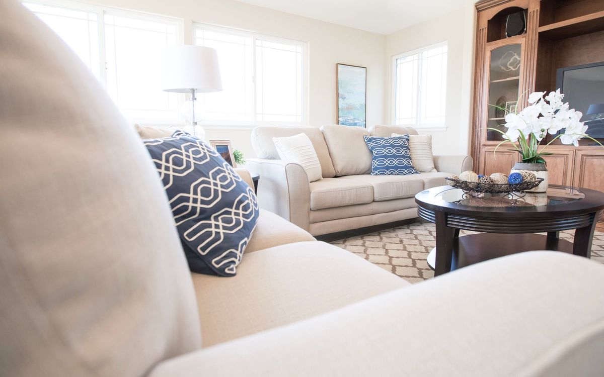 Bright living room with a cream fabric sofa, blue patterned cushions and a round coffee table.