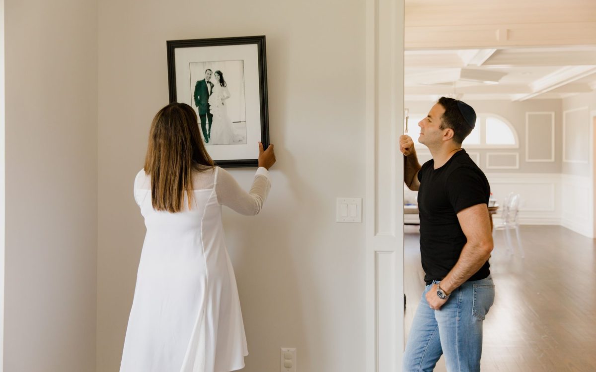 A couple decorates their modern home by hanging a framed photograph on the wall