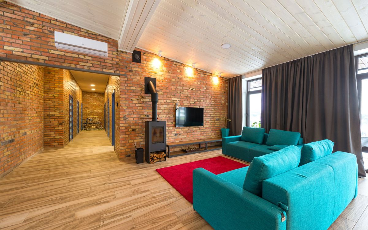Spacious living room with blue sofas, red rug, and brick walls. Cozy and contemporary interior.