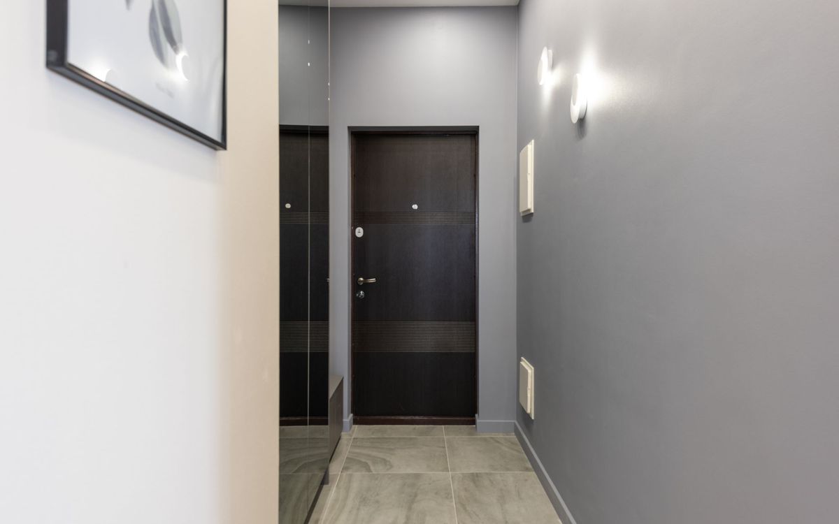 Interior of light empty hallway with white walls and parquet floor furnished with closet with mirror doors