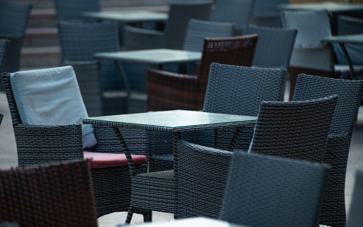 Empty outdoor terrace with wicker chairs and tables, creating a cozy café atmosphere