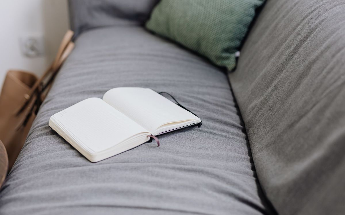 Open notebook resting on a grey sofa beside a green cushion, a reminder to write down each step and where the screws came from