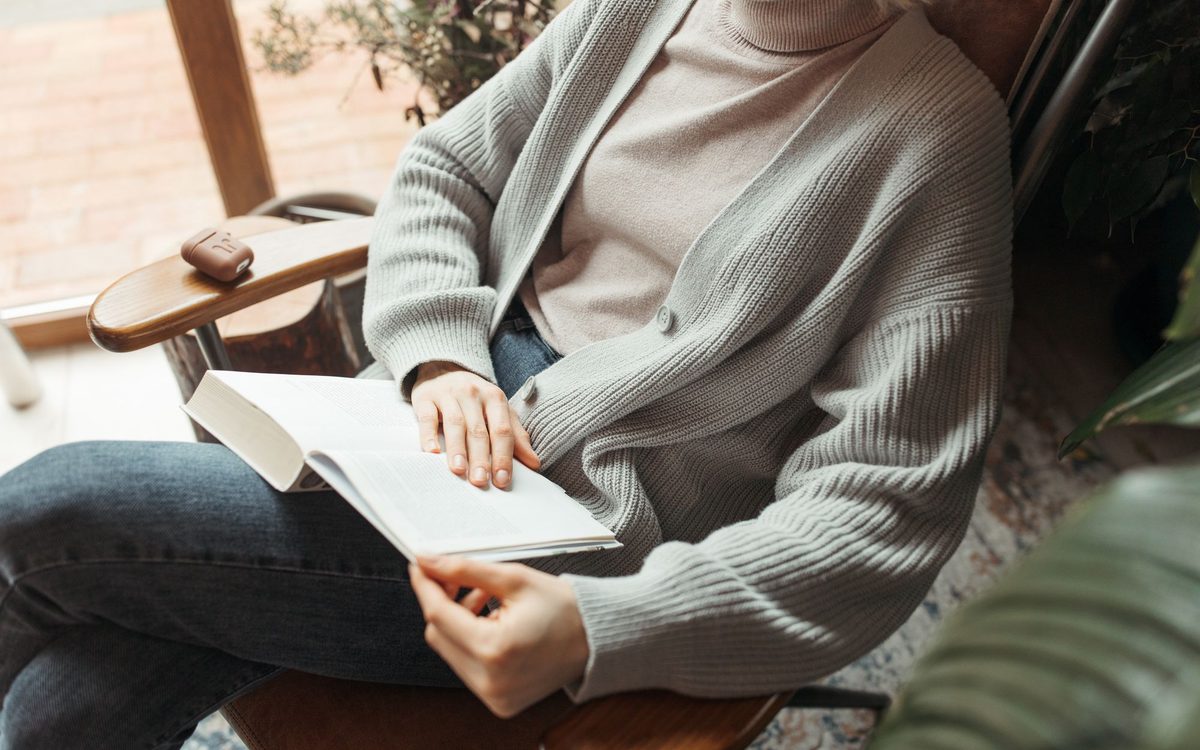 Woman relaxing indoors, reading a book in a cozy armchair