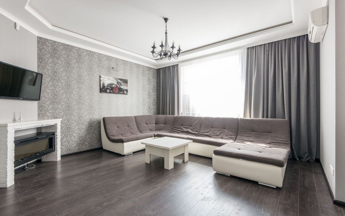 Living room with a large gray and cream wrap-around sectional facing a TV and fireplace, with a white coffee table.