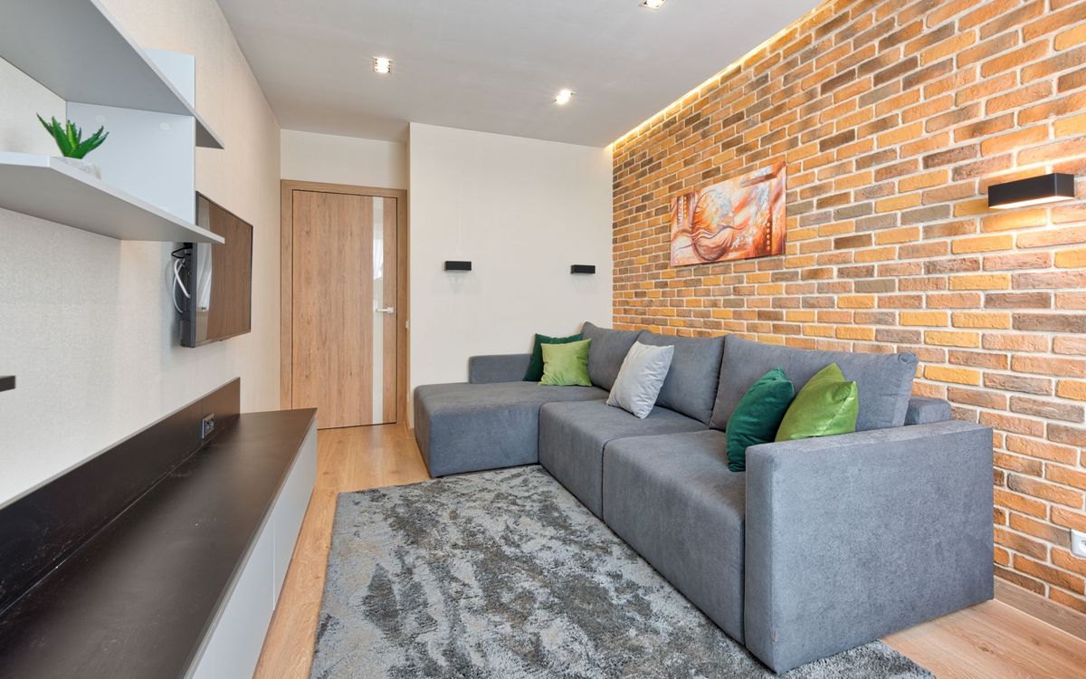 Living room with a gray L-shaped sectional sofa and chaise beside a brick wall.