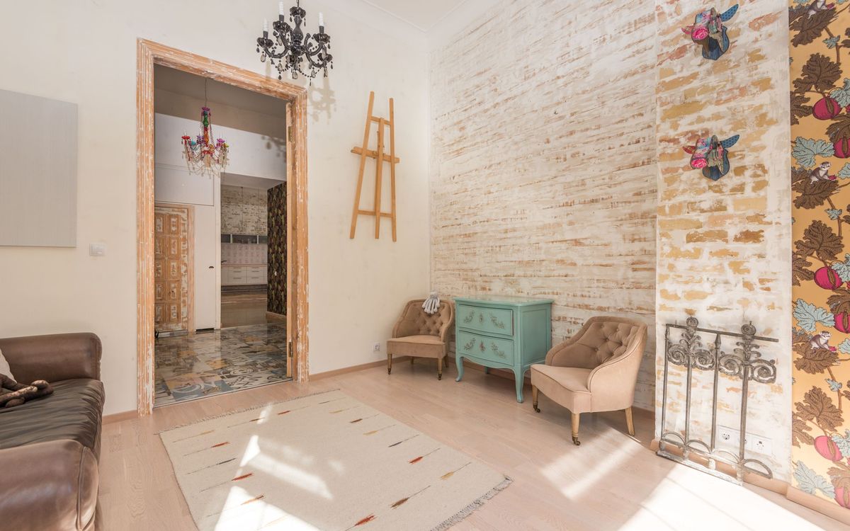 Bright living room with two upholstered armchairs set against a brick wall beside a small teal chest