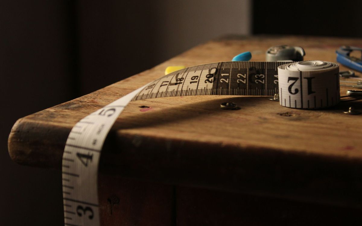 A rolled tape measure lying across the edge of a worn wooden table